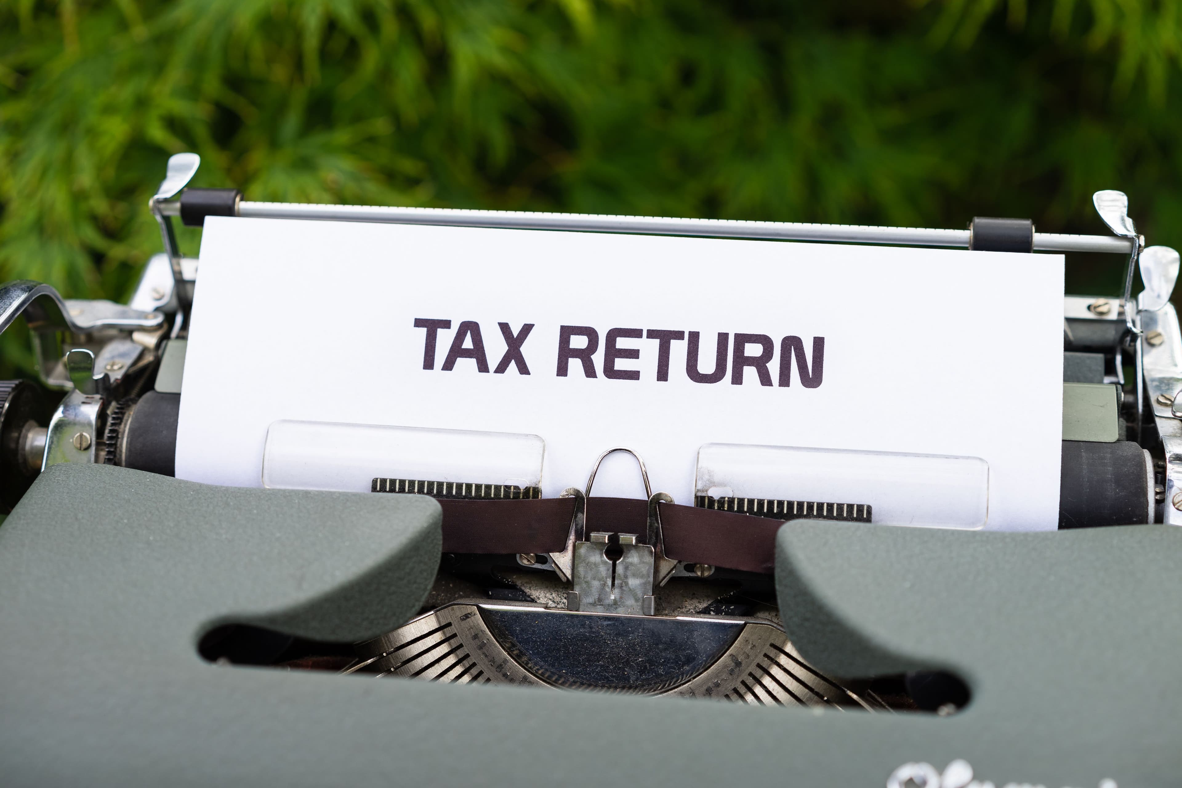 A sheet of paper in a vintage typewriter with the words "Tax Return" typed across it.